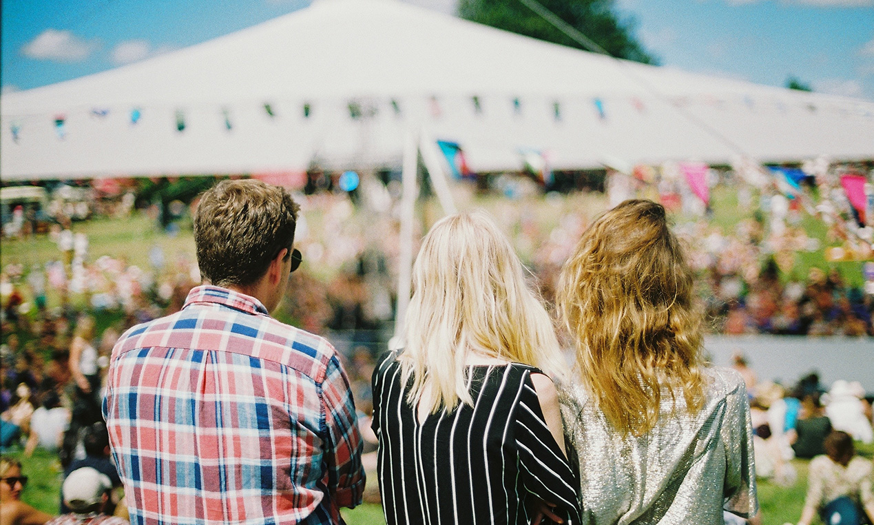 Three people stood, looking over a festival.